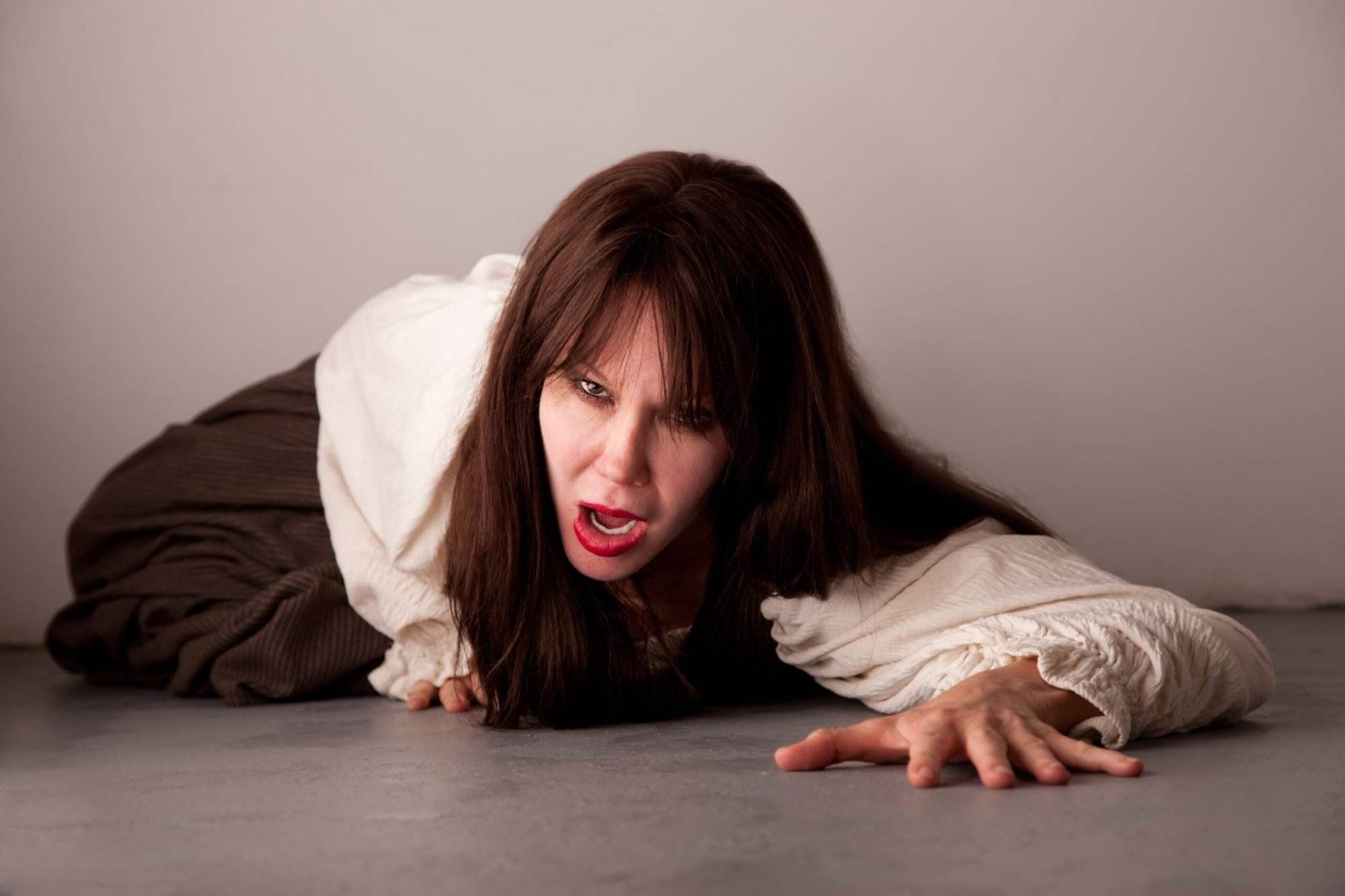 Beautiful female horror movie style victim crawling on the floor.